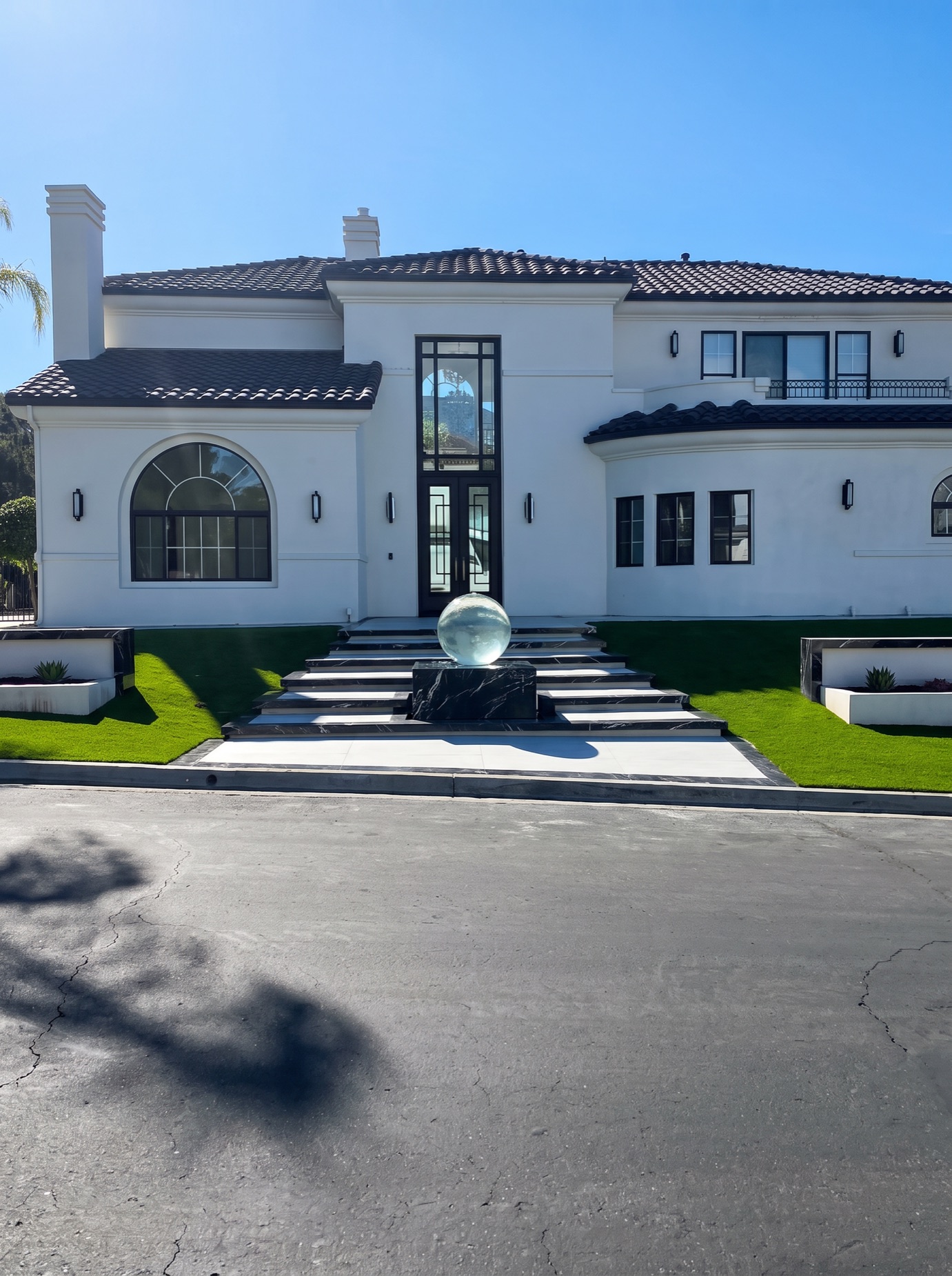 Estate entry with striped concrete steps and a lit fountain at dusk